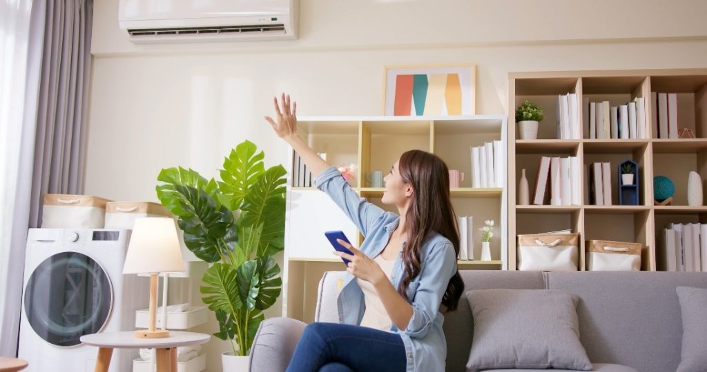 A Woman Holding Out Her Hand To Feel the Cool Air From the Air Conditioner | Air Duct Cleaning Season | Envirovac